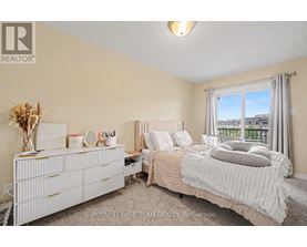 A bedroom with a large bed, a dresser, and a window with a view of the city.
