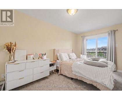 A bedroom with a large bed, a dresser, and a window with a view of the city.