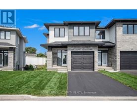 A modern house with a grey front yard is for sale.