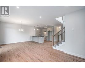 A spacious room with wooden flooring and a staircase leading to another level.