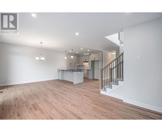 A spacious room with wooden flooring and a staircase leading to another level.