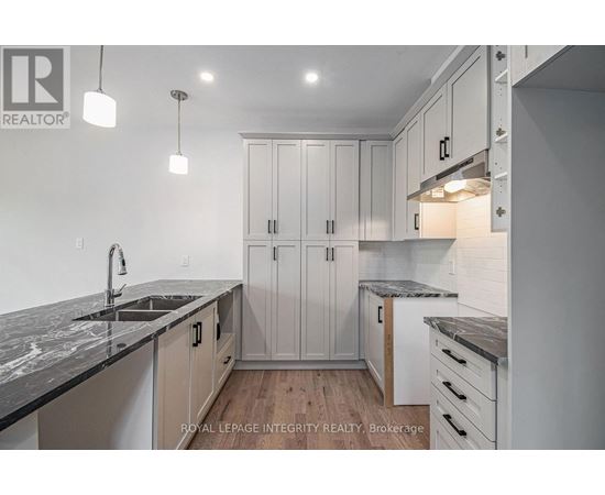A modern kitchen with white cabinets and a marble countertop.