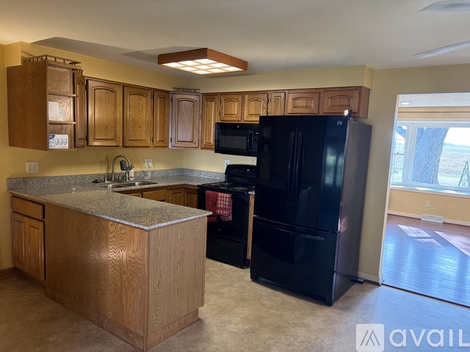 A kitchen with wooden cabinets and a black refrigerator.