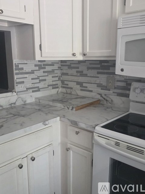 A kitchen with white cabinets and a marble countertop.