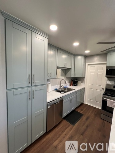 A kitchen with white cabinets and a wooden floor.