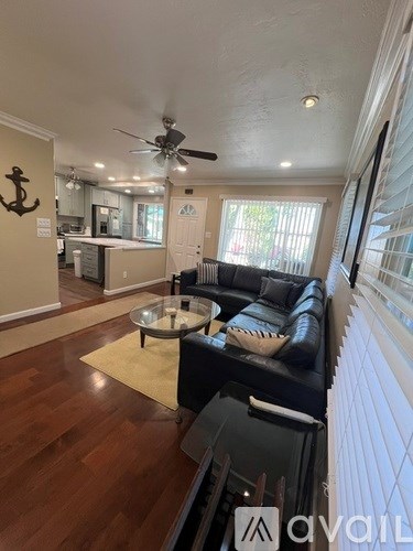 A living room with a black couch and a ceiling fan.