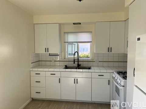 A kitchen with white cabinets and a window.
