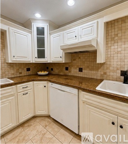 A kitchen with white cabinets and brown tiles.