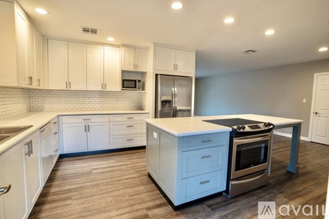 A kitchen with white cabinets and a wooden floor.