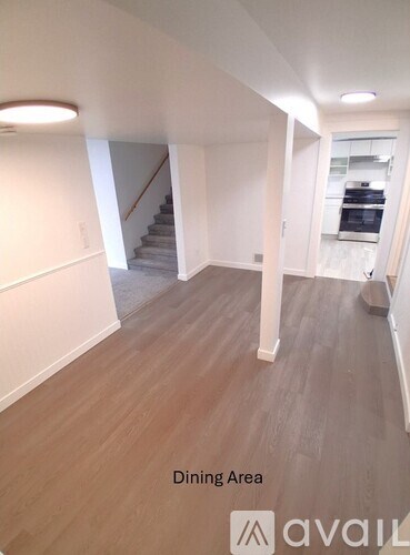 A dining area with a wooden floor and a staircase in the background.