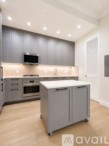 A kitchen with grey cabinets and a white island.