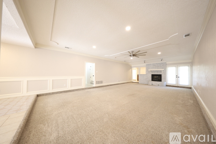 A spacious living room with a fireplace and a fan on the ceiling.