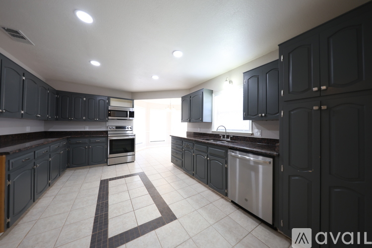 A kitchen with black cabinets and a white floor.