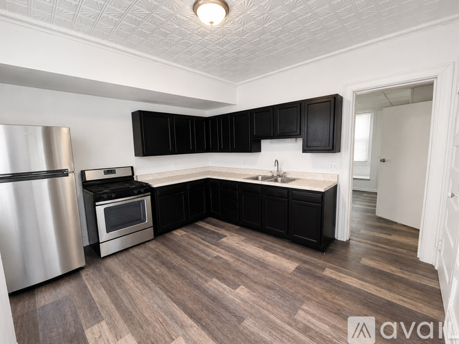 A kitchen with black cabinets and a wooden floor.