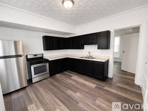 A kitchen with black cabinets and a wooden floor.