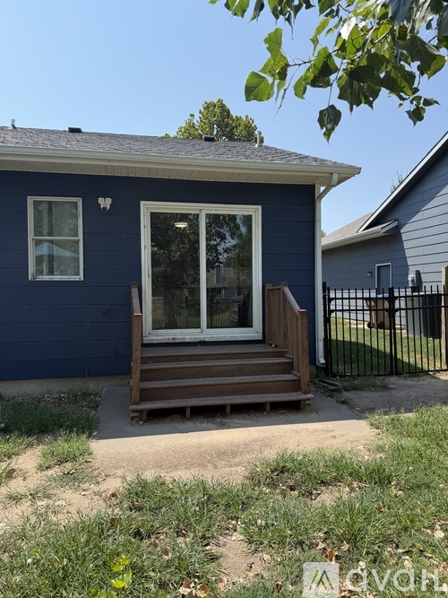 A blue house with a white window and a brown deck.