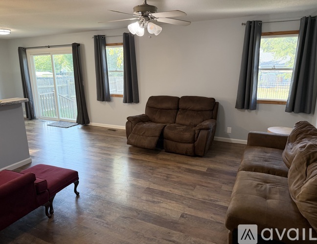 A living room with a brown couch and a ceiling fan.