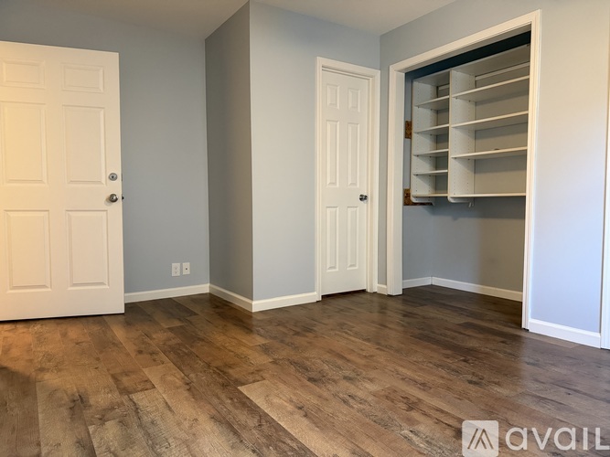 A room with a white door and a white closet with shelves.