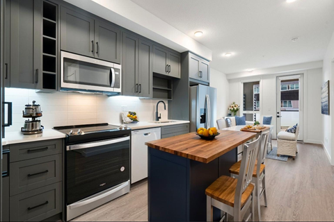 A modern kitchen with dark grey cabinets and a wooden island.