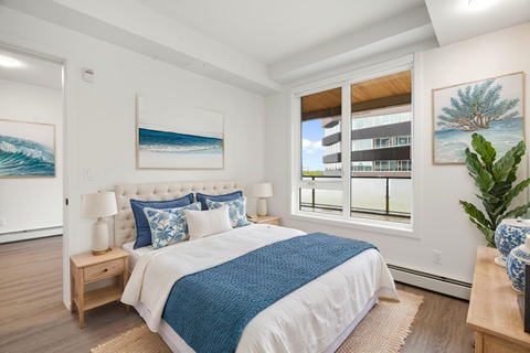 A bedroom with a large bed and a view of a building outside the window.