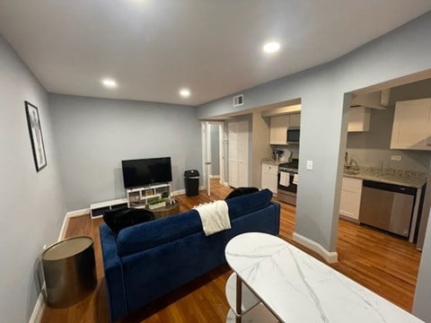 A blue couch with a white blanket on it is in the middle of a living room.