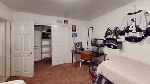 A bedroom with a bed, desk, and hockey jerseys hanging on the wall.