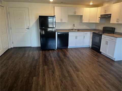 A kitchen with black appliances and white cabinets.