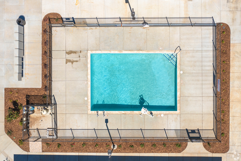 A rectangular pool surrounded by a fence and a concrete wall.