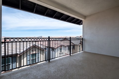 A balcony with a black railing and a view of houses and trees.