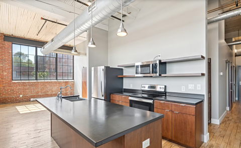 A modern kitchen with a black countertop and wooden cabinets.