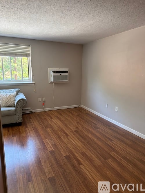 A room with wooden flooring and a window with blinds.