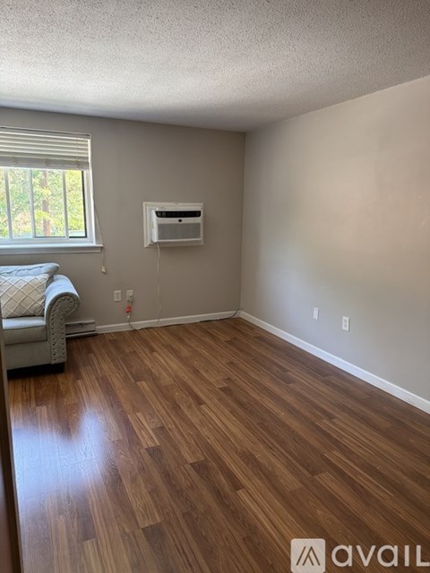 A room with wooden flooring and a window with blinds.