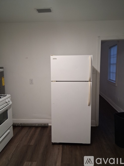 A white refrigerator in a kitchen with wood flooring.