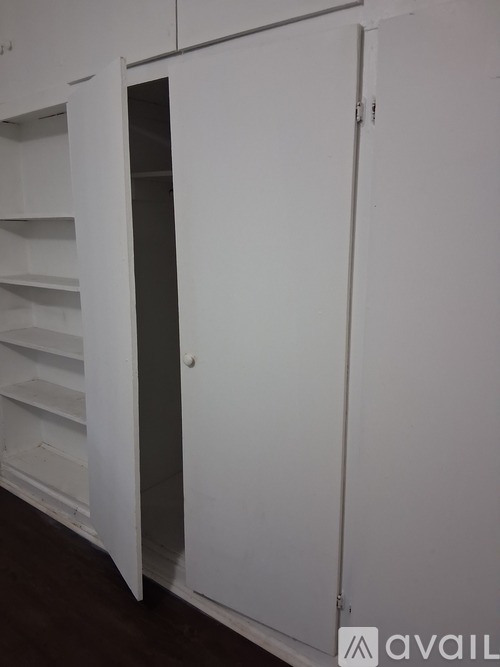 A white cabinet with a door open to a dark interior.