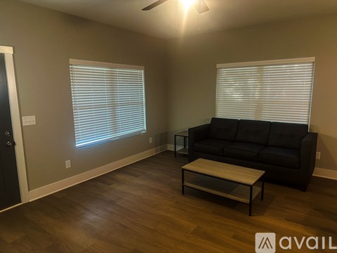 A living room with a black couch and a wooden coffee table.