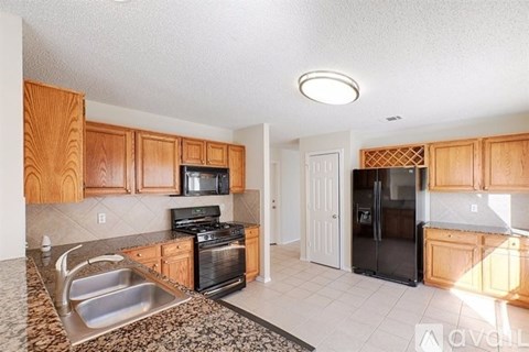 A kitchen with wooden cabinets and a black refrigerator.