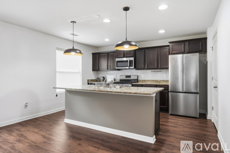 A kitchen with a refrigerator, microwave, and cabinets.
