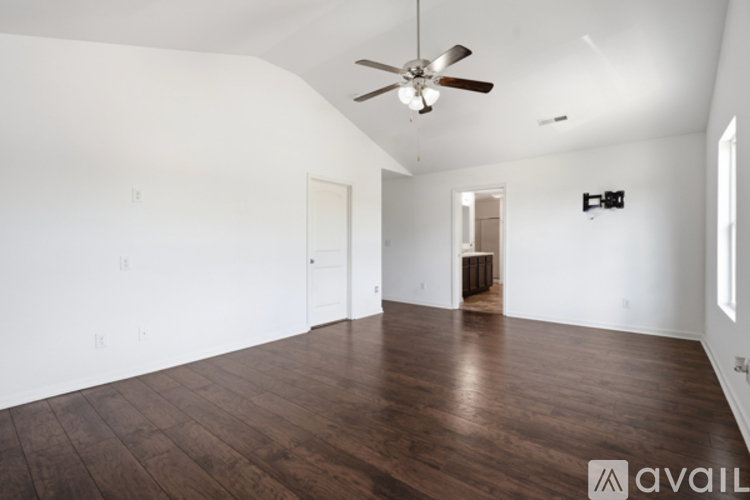 A spacious room with a ceiling fan and wooden flooring.