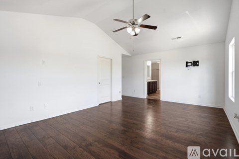 A spacious room with a ceiling fan and wooden flooring.