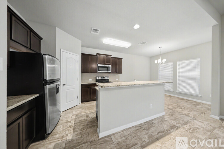 A kitchen with a refrigerator, microwave, and oven is available for rent.