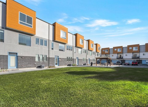A row of modern townhouses with a grassy area in front.
