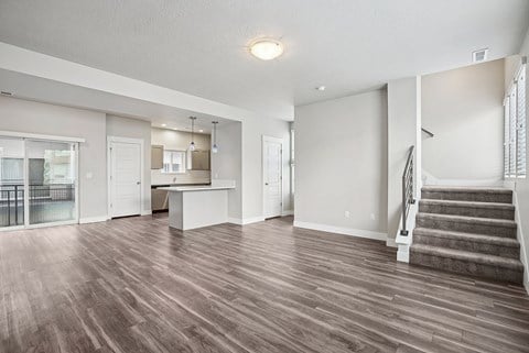 A spacious living room with hardwood floors and a staircase.