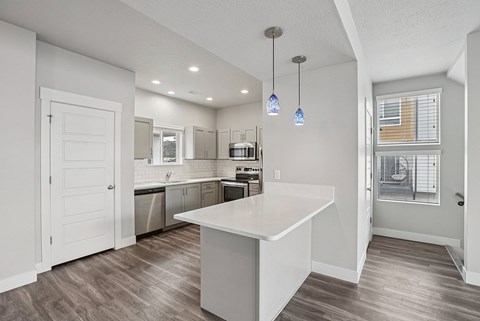 A kitchen with a white island and wooden floors.