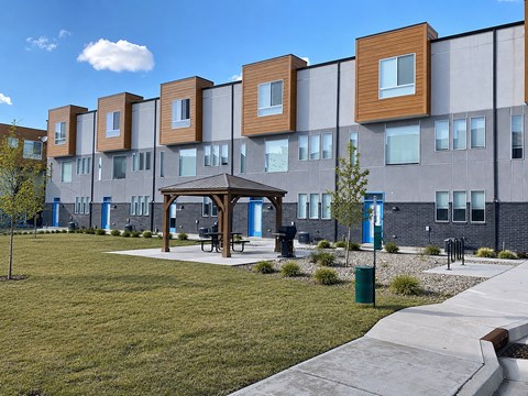 A modern building with a grassy area in front and a pavement leading to a gazebo.