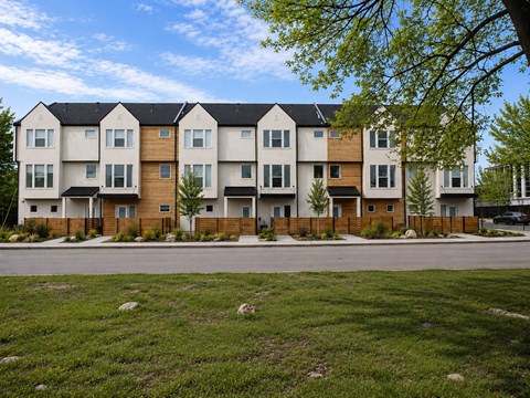 A row of modern townhouses with a grassy front yard.