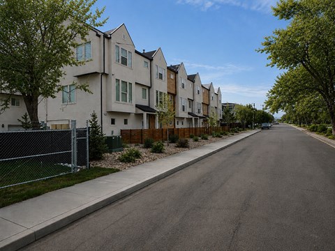 A row of houses with a sidewalk and a tree on the left.