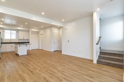 A spacious room with wooden flooring and white walls.