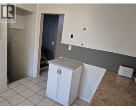 A white cabinet with a granite countertop is in a room with a grey wall and a door.