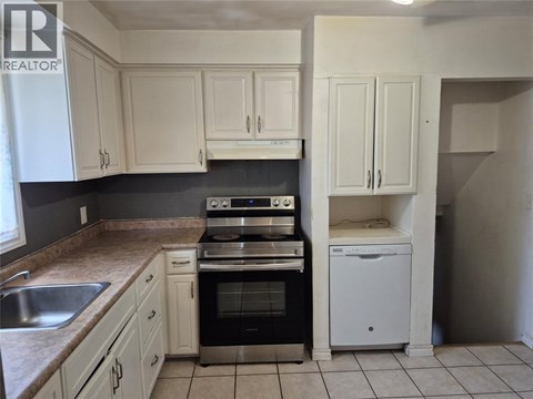 A kitchen with white cabinets and a black stove top oven.