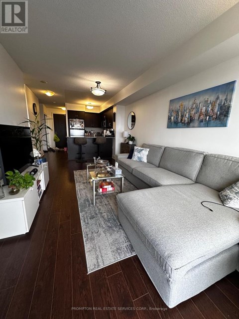 A living room with a grey couch and a painting on the wall.